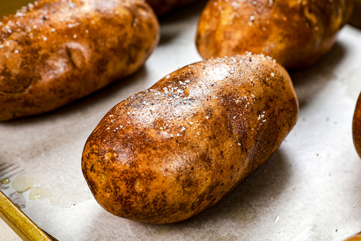 showing how to make a baked potato in the oven by seasoning with salt and pepper