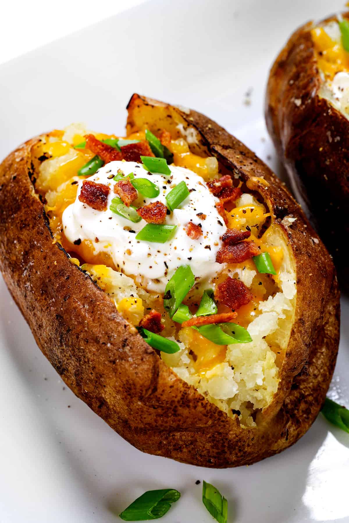 baked potato recipe being served with cheese, bacon, sour cream and green onions