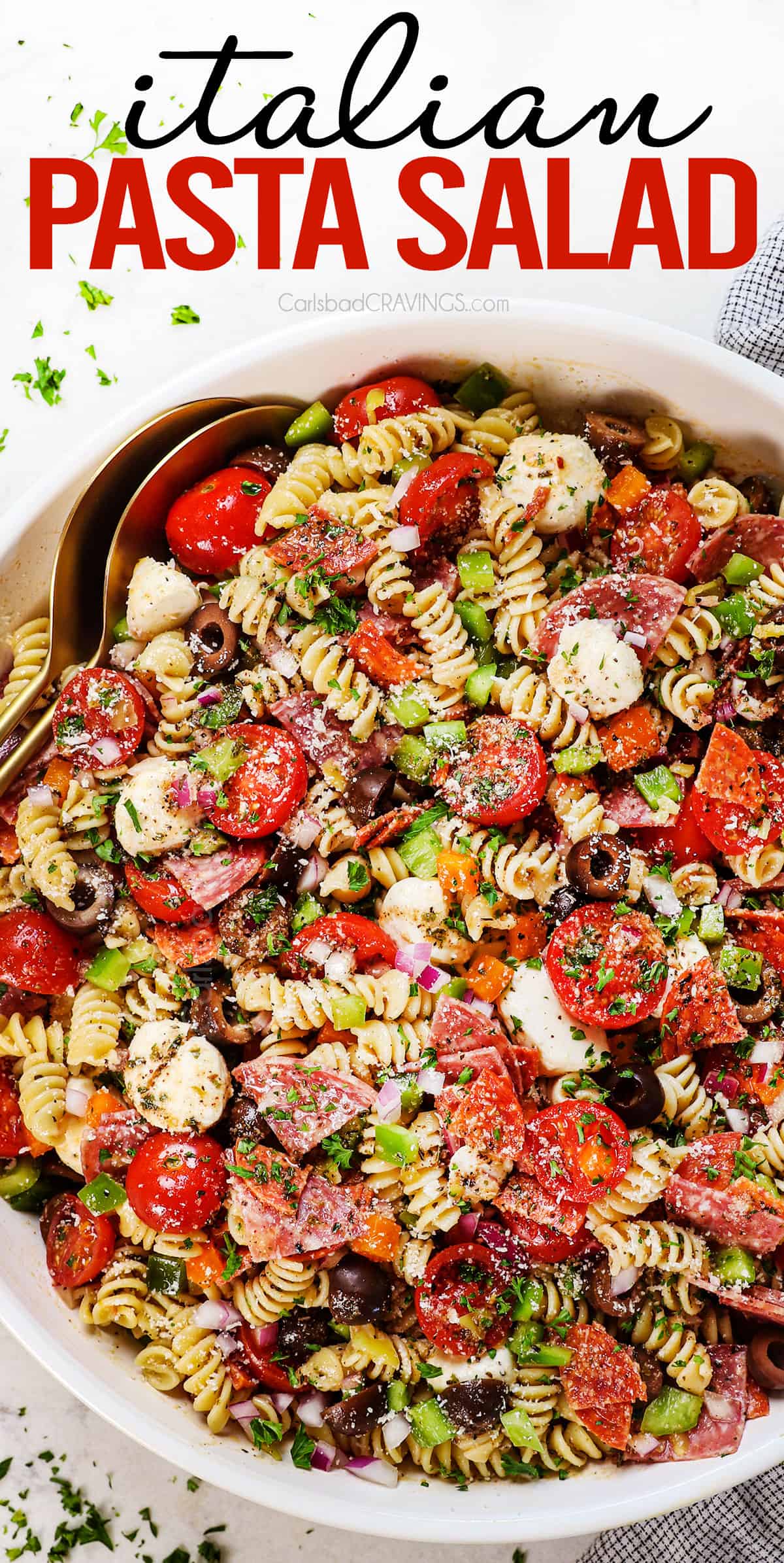 top view of pasta salad recipe in a bowl with salami, tomatoes, bell peppers, olives, pepperoncini, Parmesan and parsley