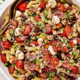 top view of pasta salad recipe in a bowl with salami, tomatoes, bell peppers, olives, pepperoncini, Parmesan and parsley
