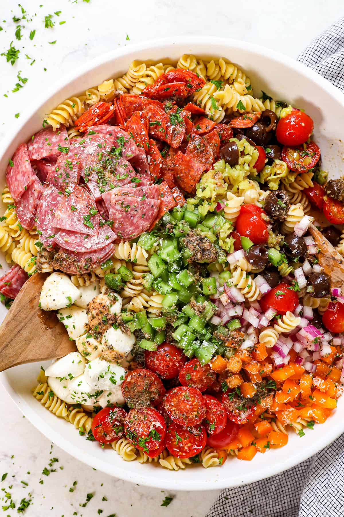 top view tossing italian pasta salad recipe ingredients together