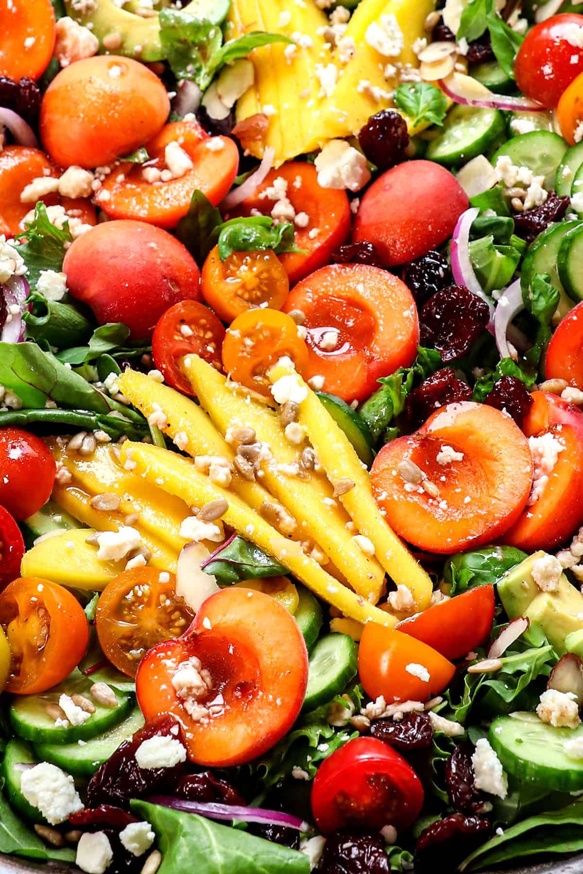 showing how to make summer salad by drizzling dressing over salad