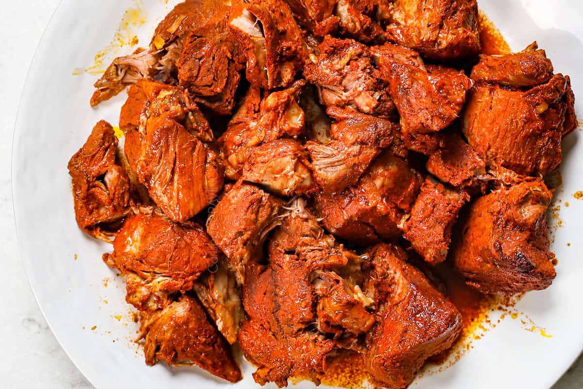 showing how to make cochinita pibil recipe by transferring the pork to a cutting board after slow roasting 