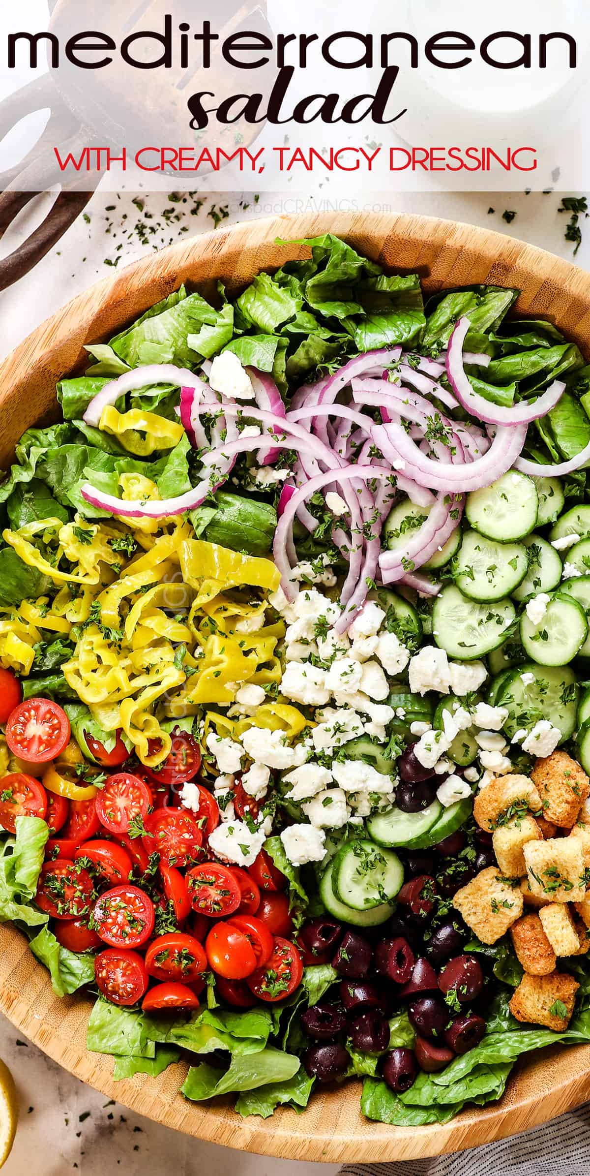 top view of adding Mediterranean salad recipe ingredients to a a bowls:  cucumbers, red onions, tomatoes, feta, olives, pepperoncini and Romaine letttuce