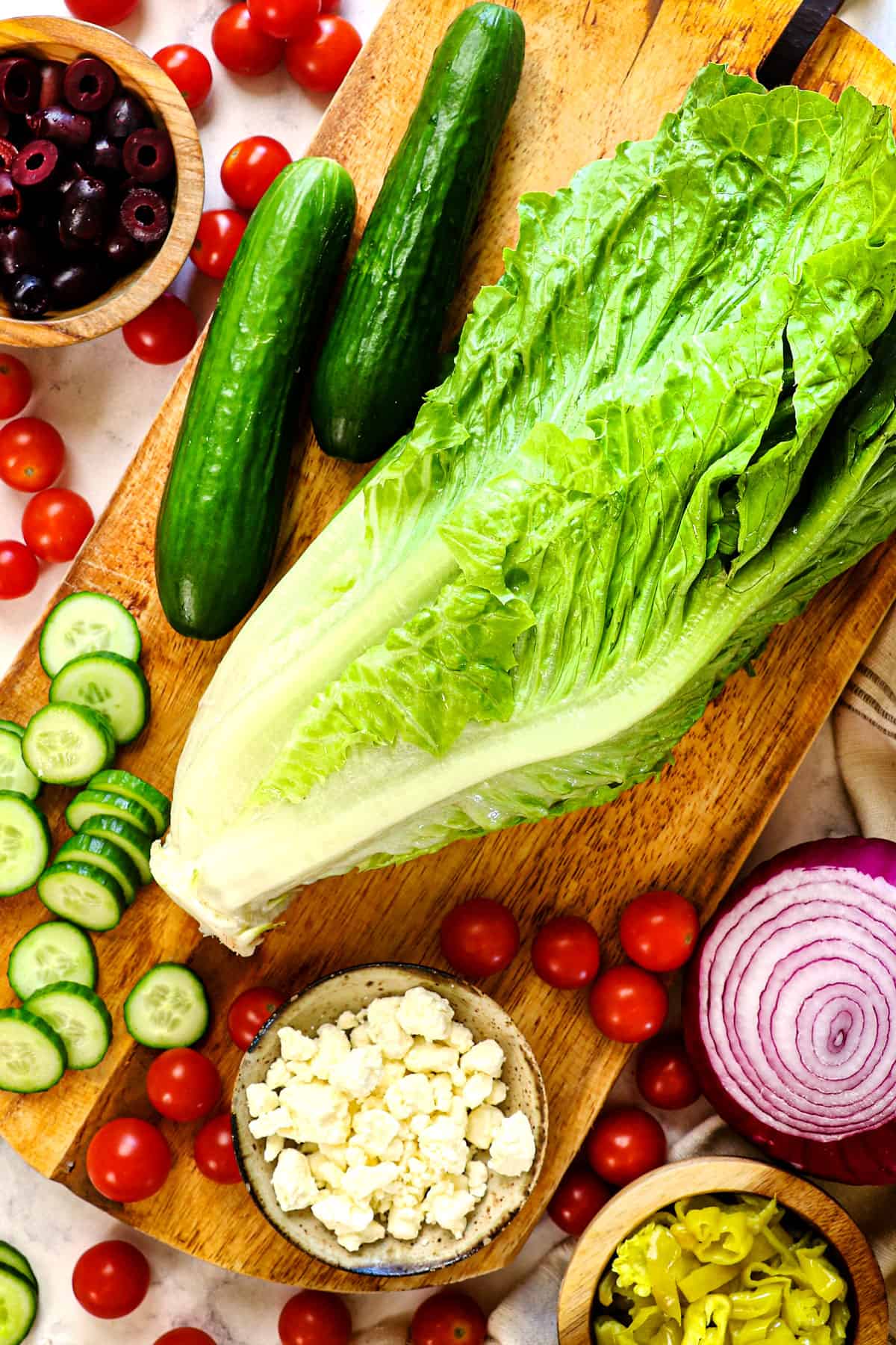 top view of Mediterranean Salad ingredients: Romaine lettuce, tomatoes, cucumbers, Kalamata olives, red onions, feta, pepperoncini