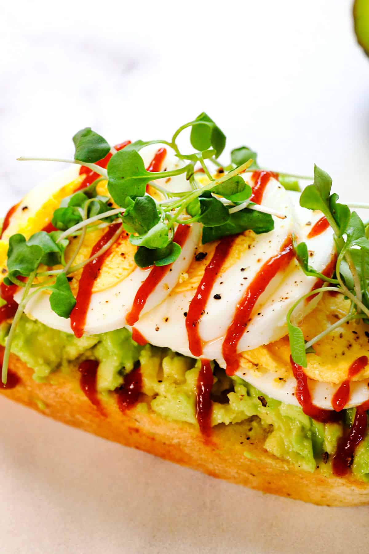 up close of best avocado toast topped with mashed avocado and egg