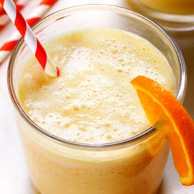 up close of orange Julius served in a glass with an orange and white striped straw