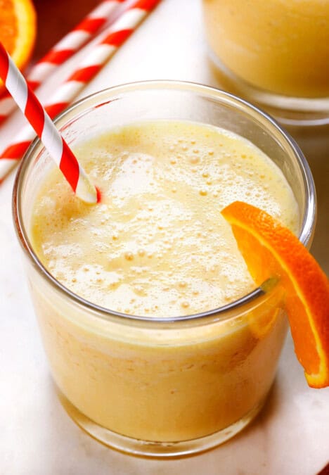 up close of orange Julius served in a glass with an orange and white striped straw