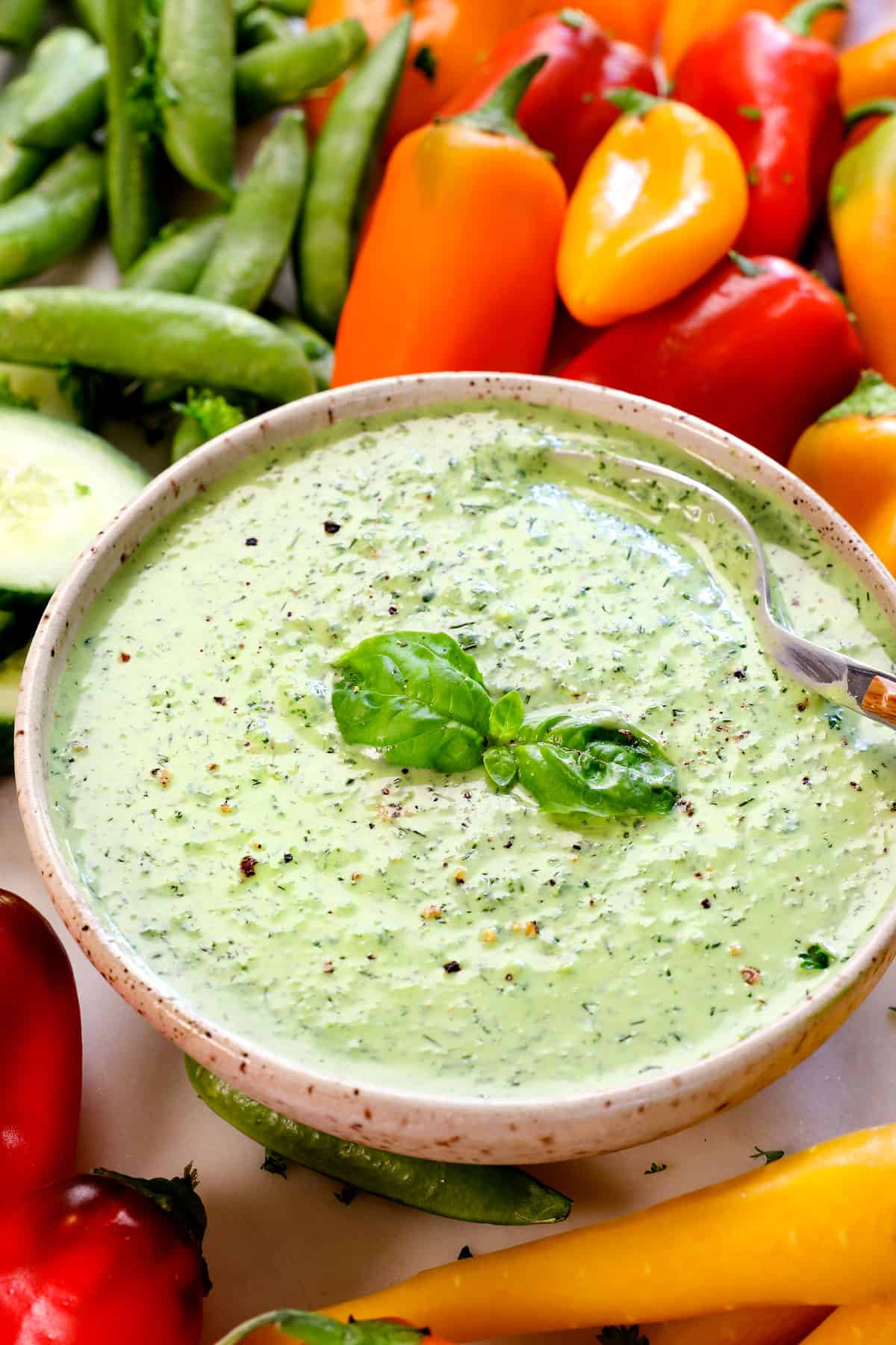 showing how thick and creamy green goddess salad dressing is in a bowl with a spoon