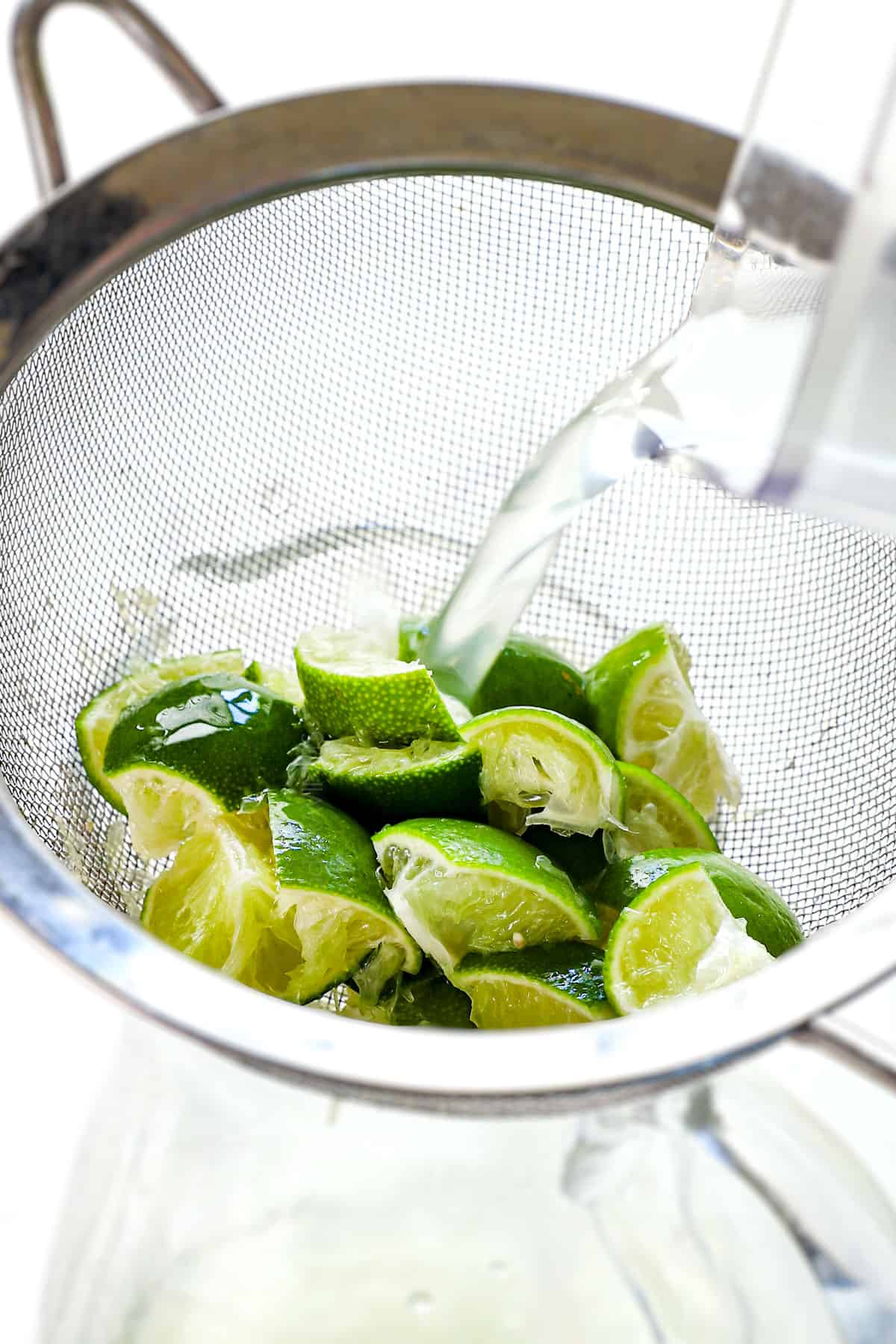 showing how to make Brazilian Lemonade by straining the mixture through a fine mesh sieve