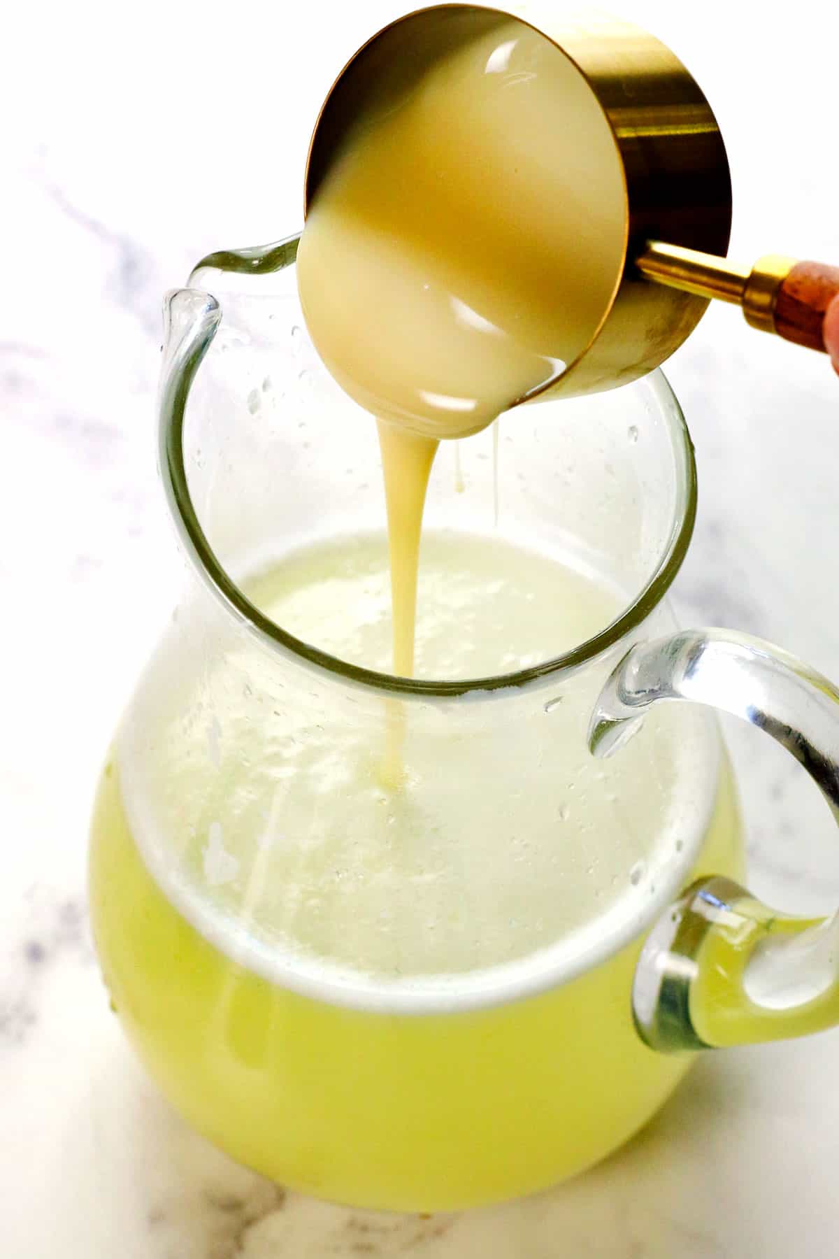 showing how to make Brazilian Lemonade by adding the sweetened condensed milk and whisking vigorously to combine