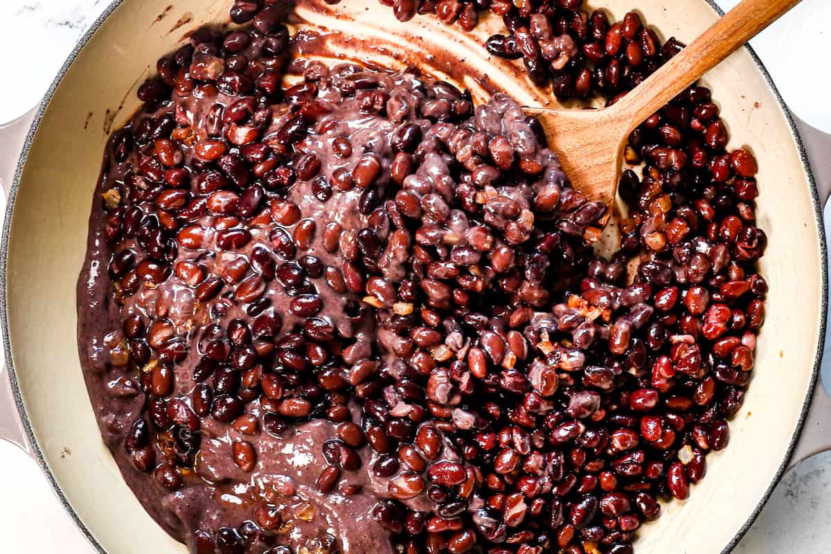 showing how to cook black beans by adding black beans, pureed black beans, water and chicken bouillon to the sautéed aromatics in the pot