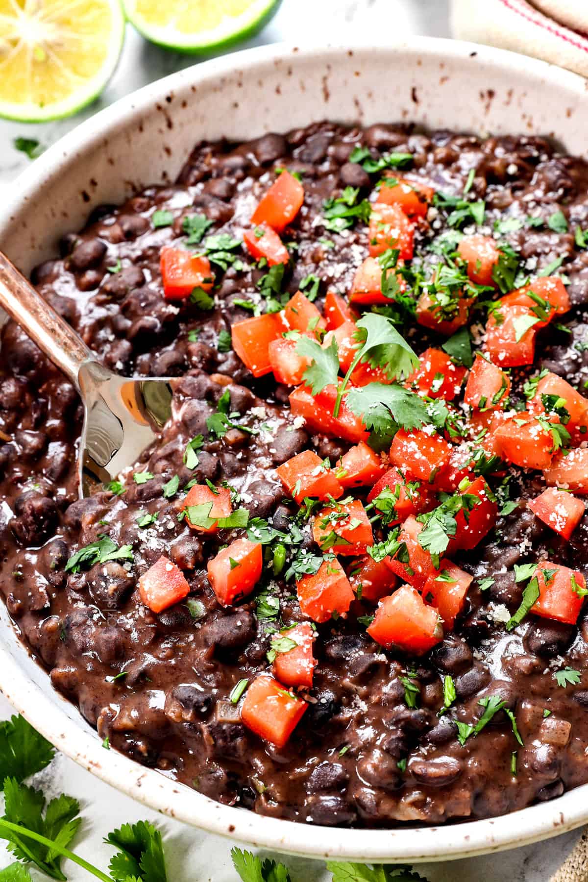 a bowl of black bean recipe garnished with cilantro, tomatoes and Cotija cheese