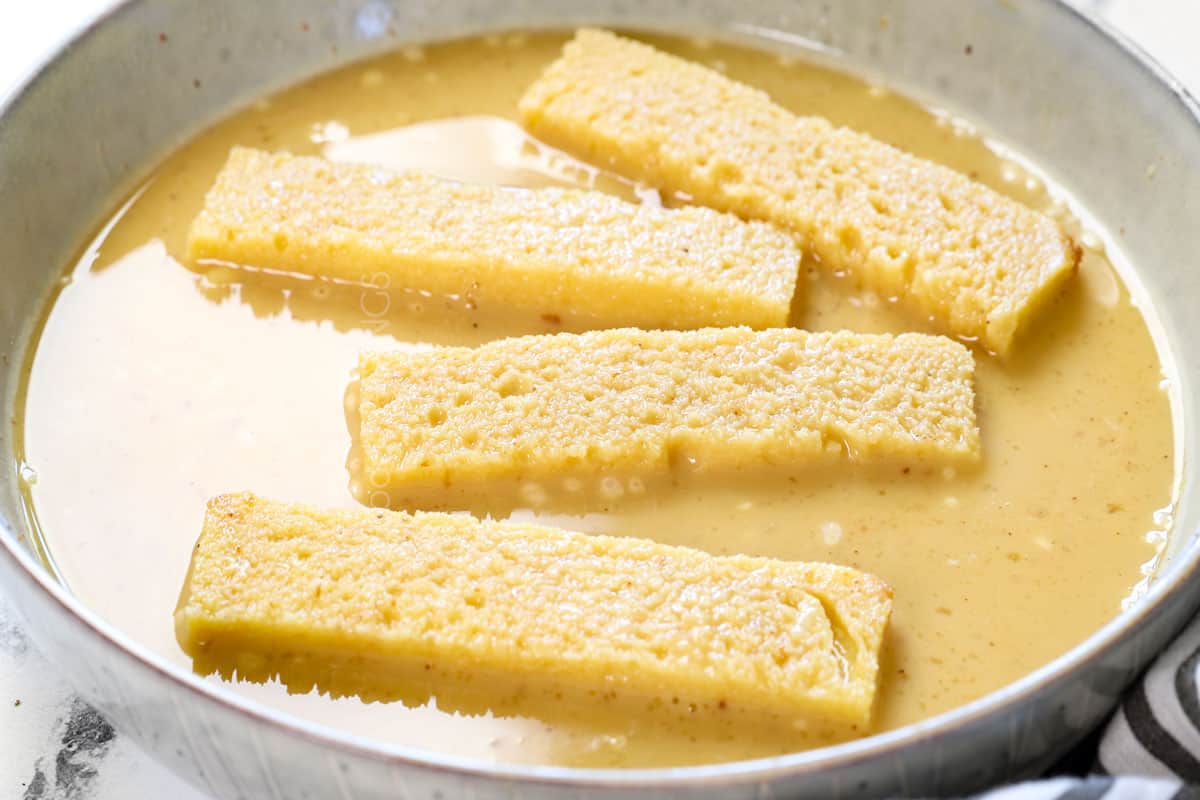 showing how to make French toast sticks by battering the sticks in the custard in a bowl