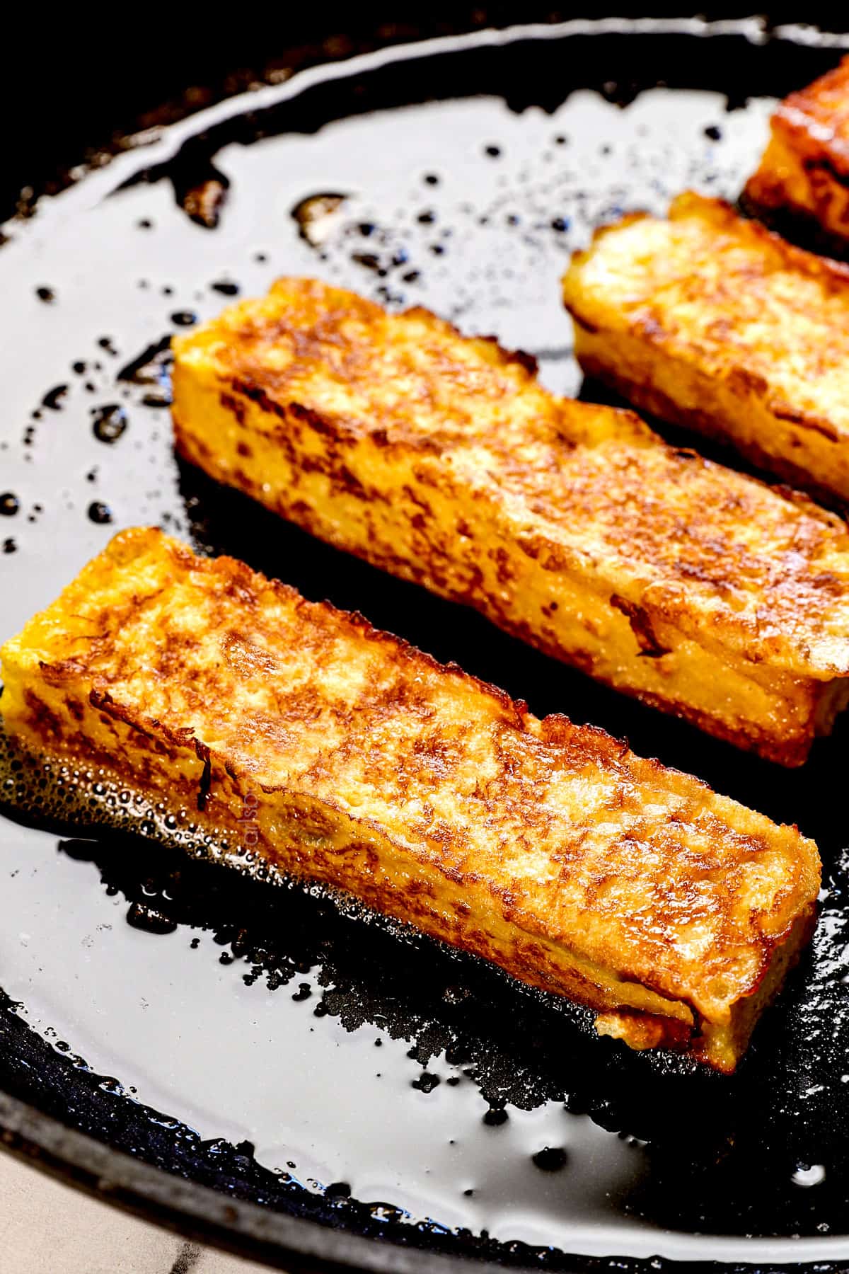 showing how to make French toast sticks by cooking them in a skillet