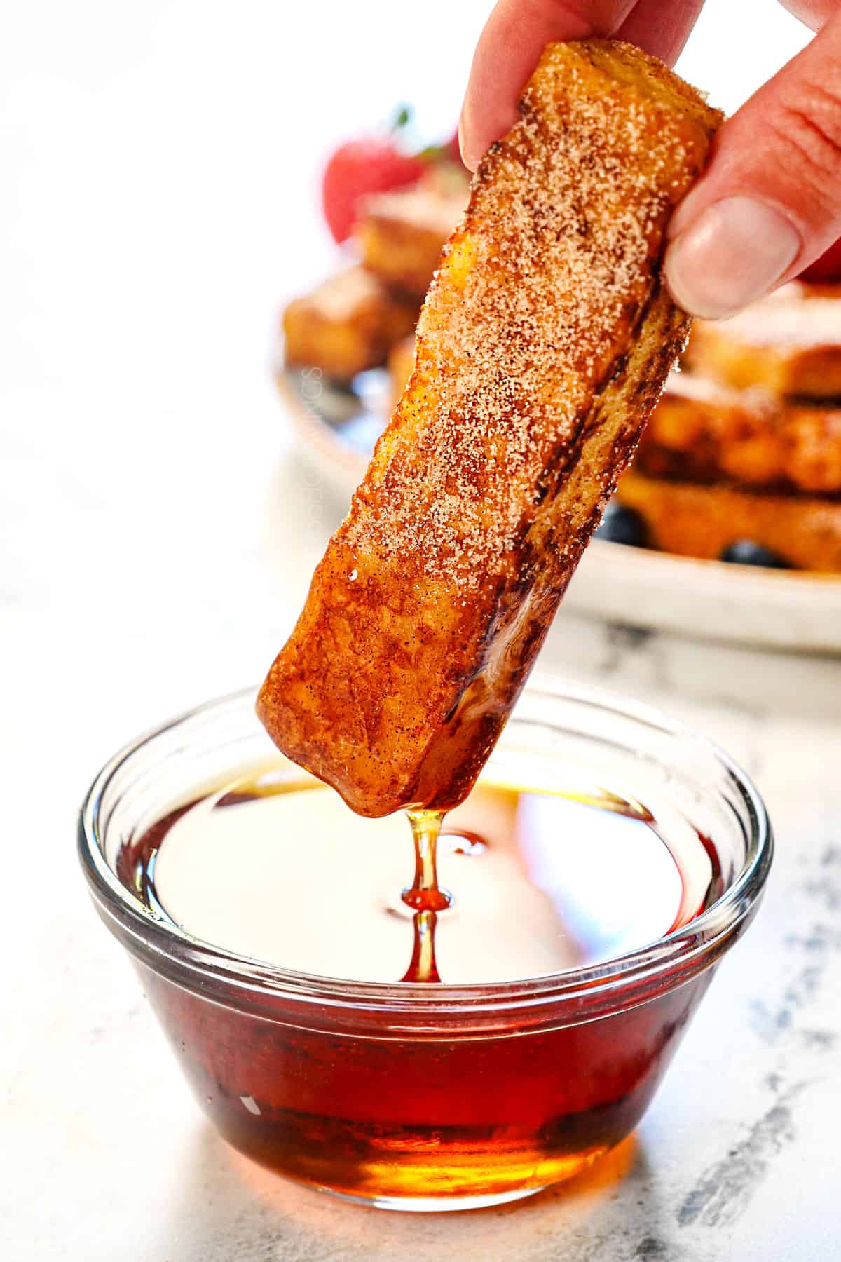 showing how to serve French toast sticks by dunking them in syrup