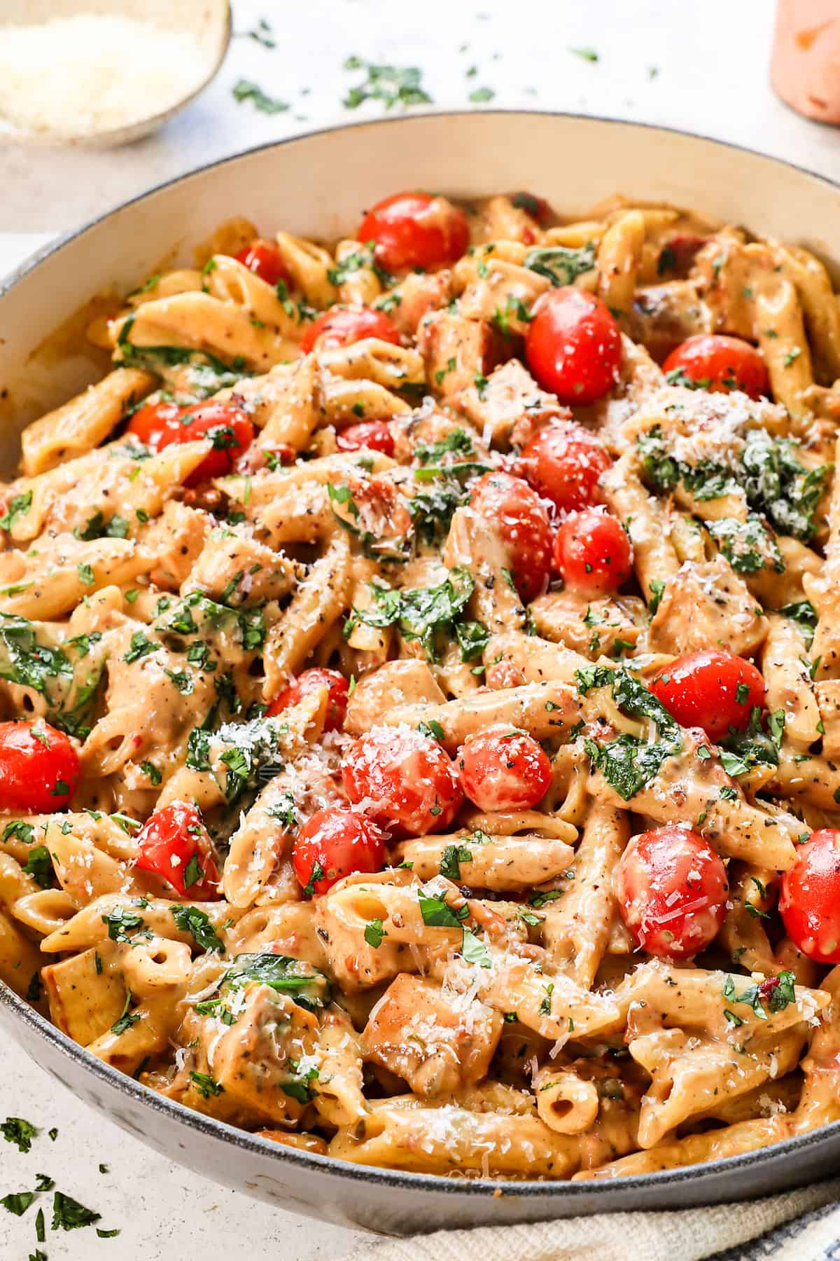 creamy Tuscan chicken pasta being served in a pan garnished with parsley