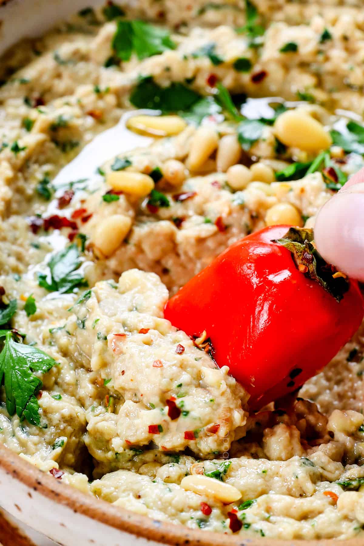 showing how to serve baba ghanoush by dipping a bell pepper in it as a dip