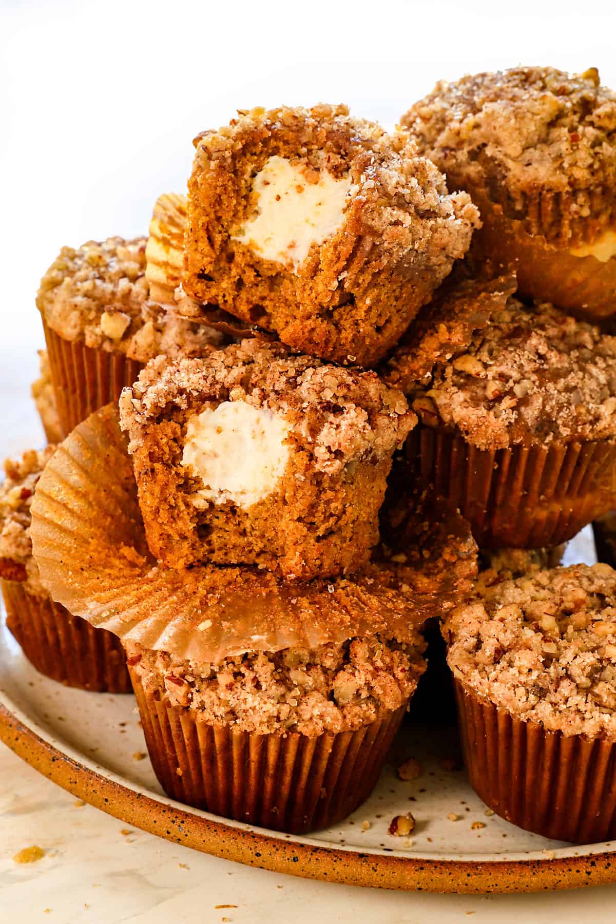 pumpkin cream cheese muffins on a plate with bites taken out of two of the muffins showing the cream cheese centers