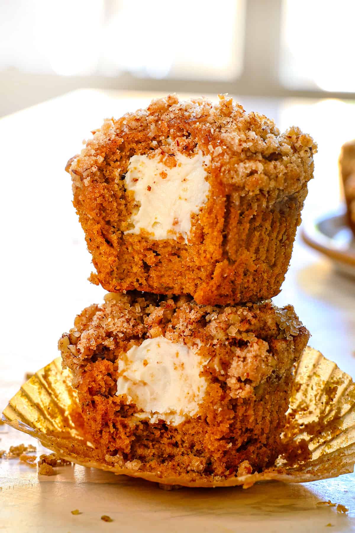 2 cream cheese pumpkin muffins with bites taken out showing the creamy centers, stacked