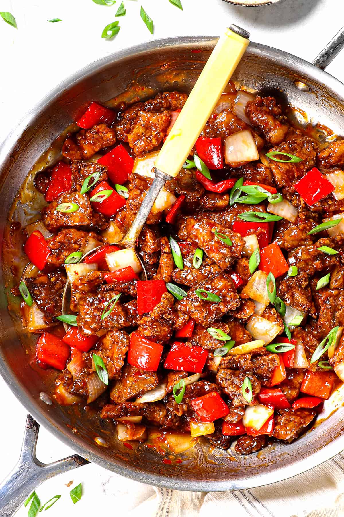 top view of Beijing beef panda express recipe garnished by green onions in a skillet