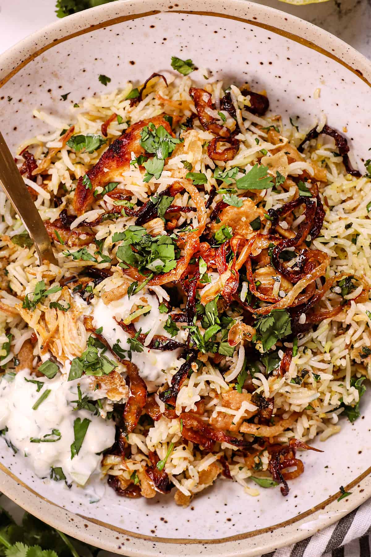 up close of serving biryani recipe garnished with mint, cilantro, served with raita