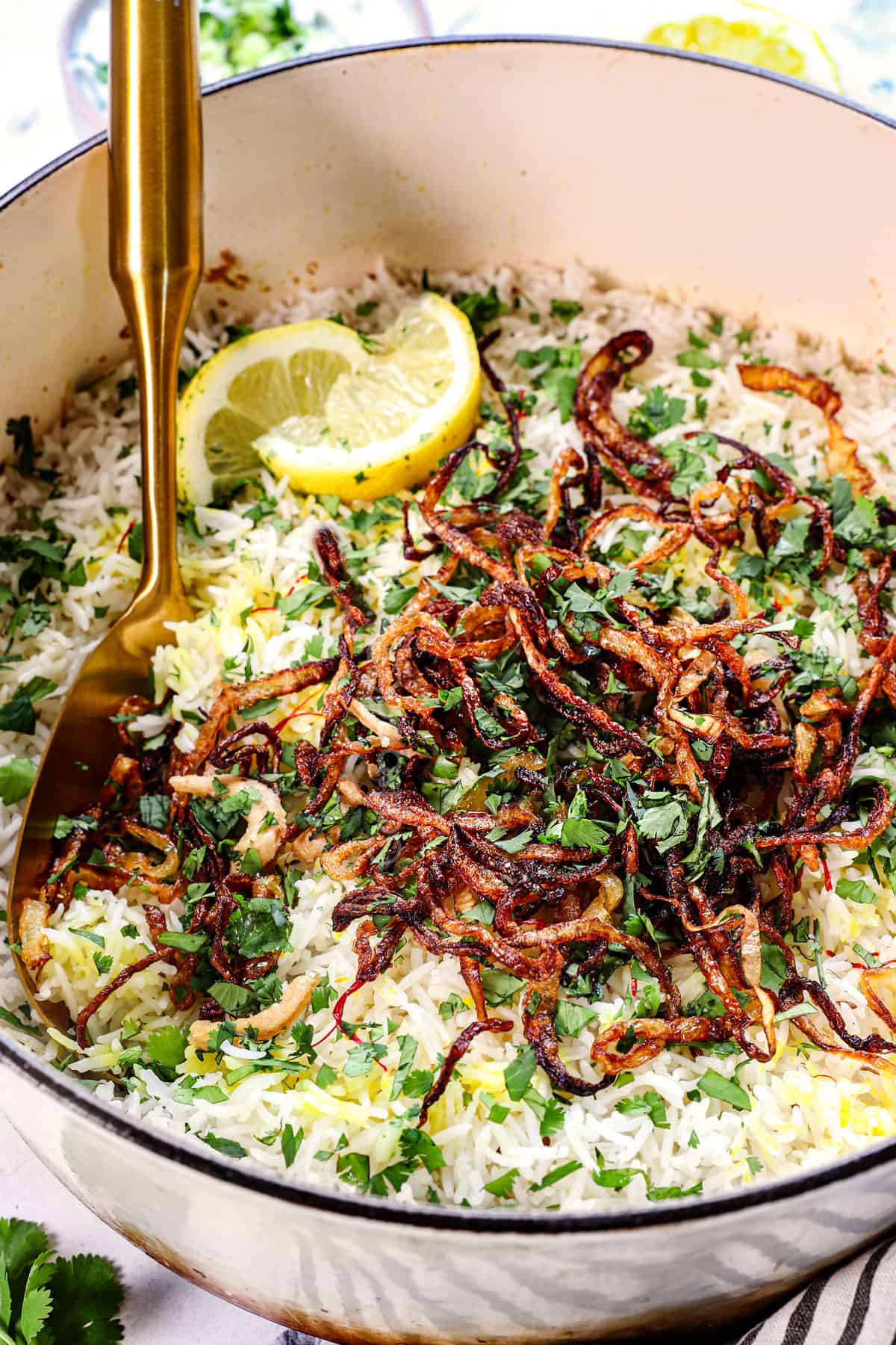 showing how to serve biryani recipe by topping the cooked rice with fried onions