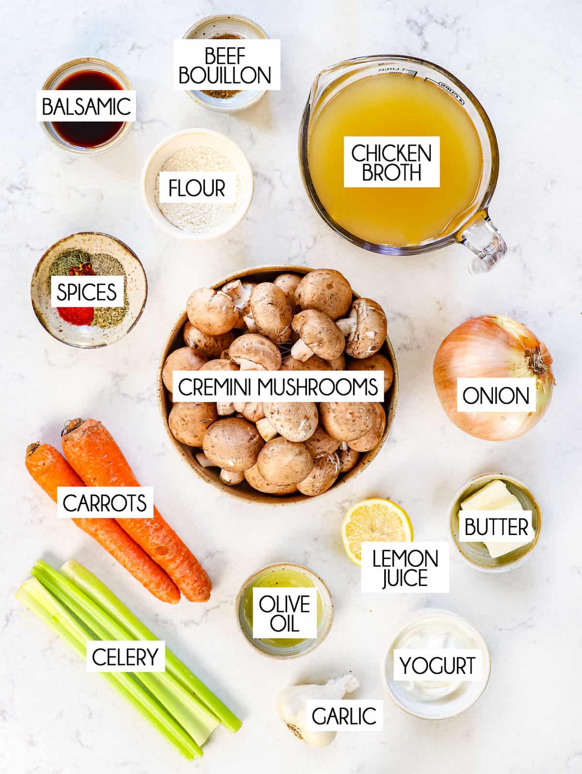 top view showing ingredients for mushroom soup:  cremini mushrooms, chicken broth, onion, garlic, celery, carrots, spices, flour, balsamic, and lemon juice