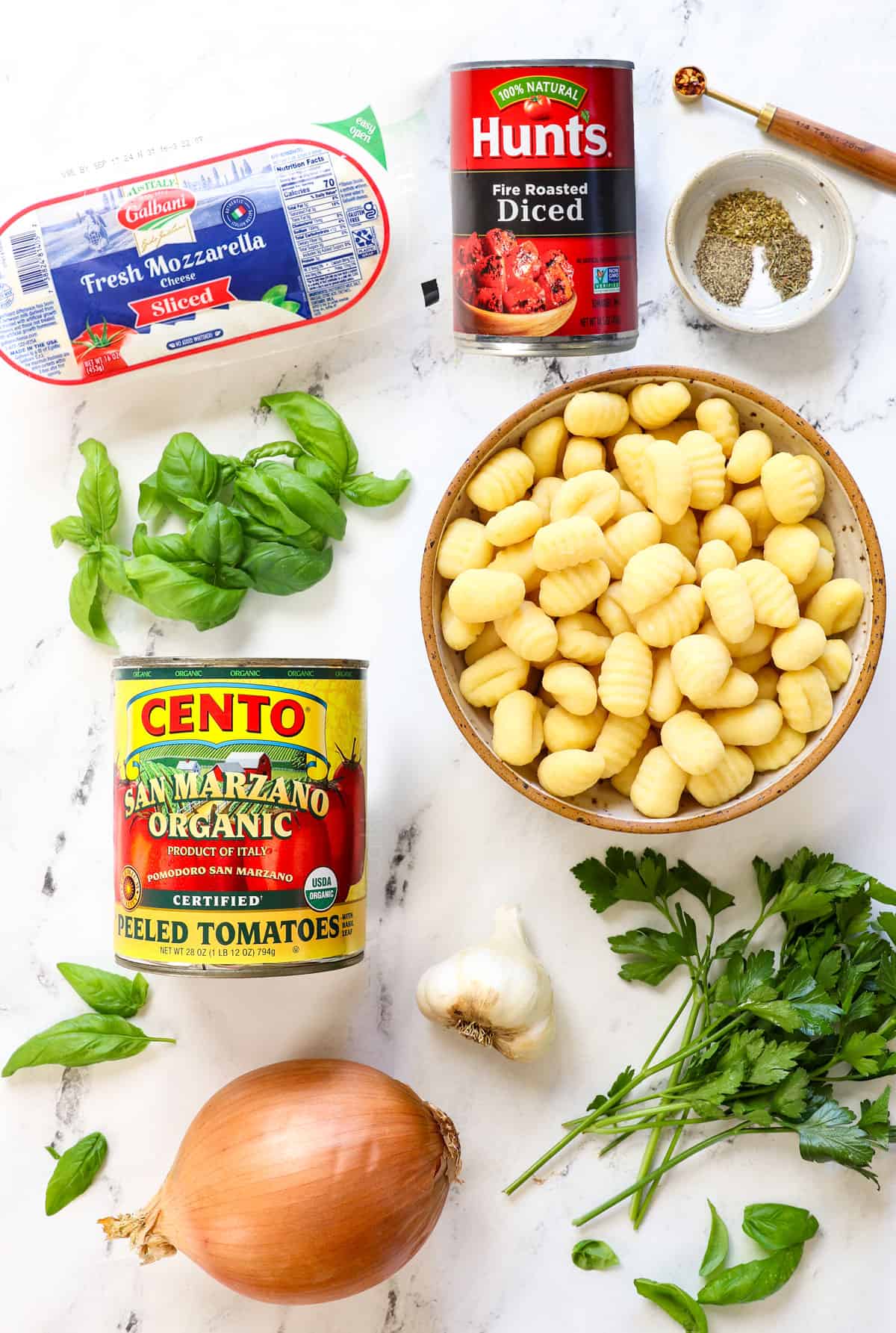 top view of gnocchi recipe ingredients:  homemade gnocchi, San Marzano tomatoes, fire-roasted diced tomatoes, fresh mozzarella, fresh basil, fresh parsley, spices, onion, garlic and red pepper flakes 