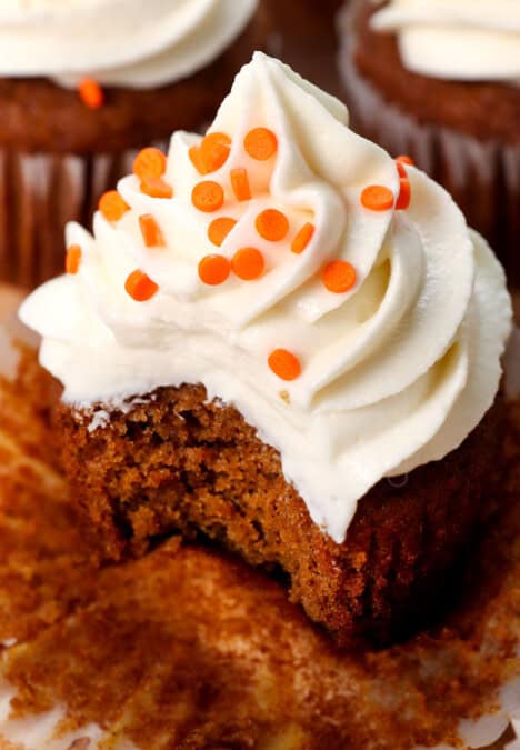 up close of pumpkin cupcakes with cream cheese frosting with a bite taken out of it, showing how soft, tender and moist it is