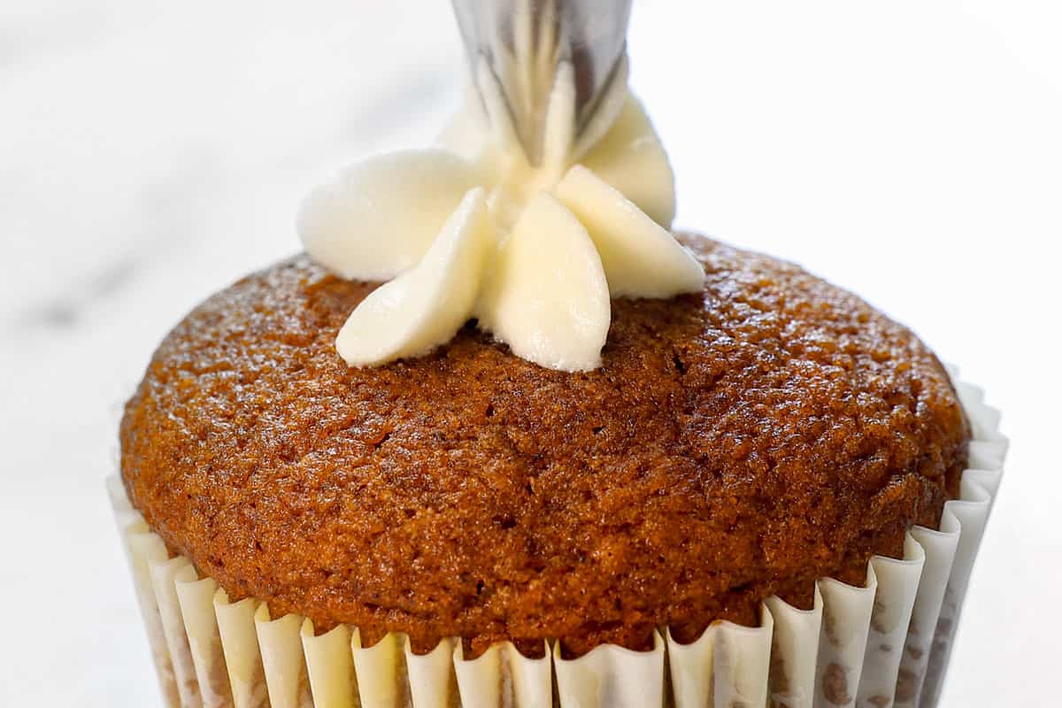 showing how to make pumpkin cupcakes by frosting the cupcakes