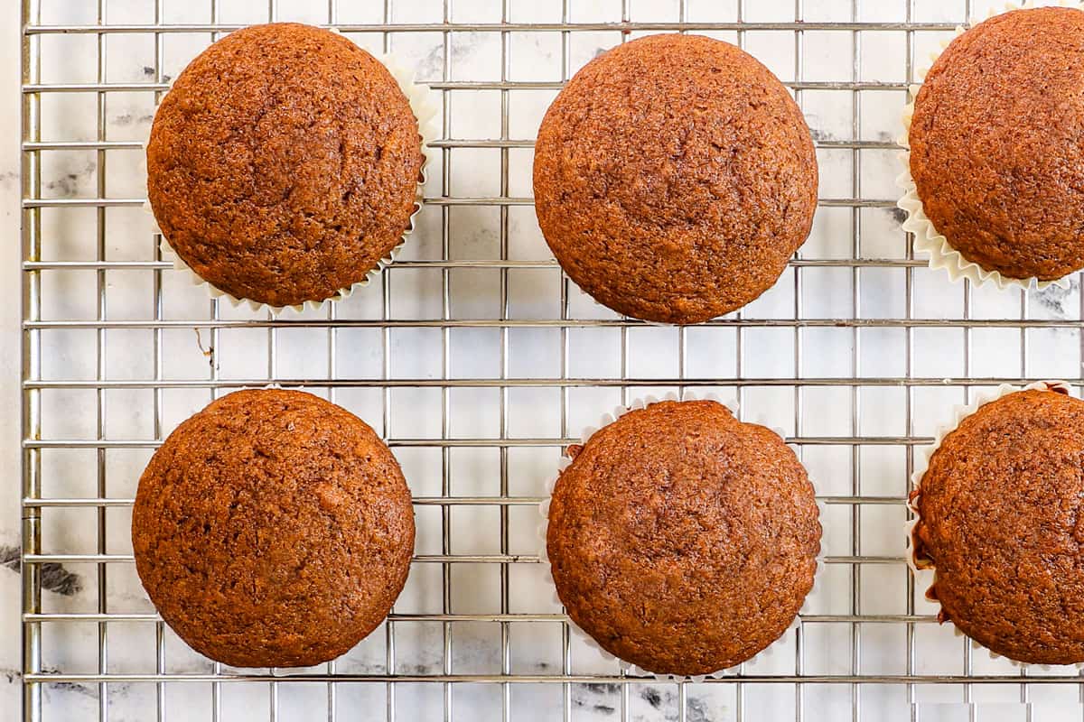 showing how to make pumpkin cupcakes by cooling the cupcakes on a wire rack before frosting