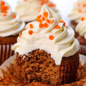 up close of pumpkin cupcakes with cream cheese frosting with a bite taken out of it, showing how soft, tender and moist it is