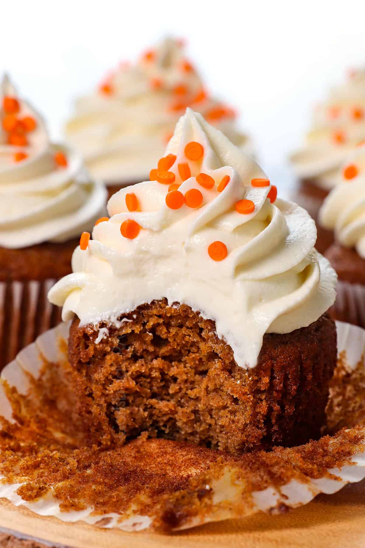 up close of pumpkin cupcakes with  a bite taken out of it, showing how moist it is