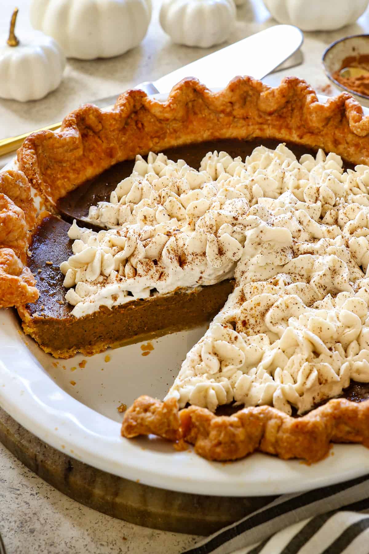 showing how to garnish best pumpkin pie recipe by piping whipped cream over the filling