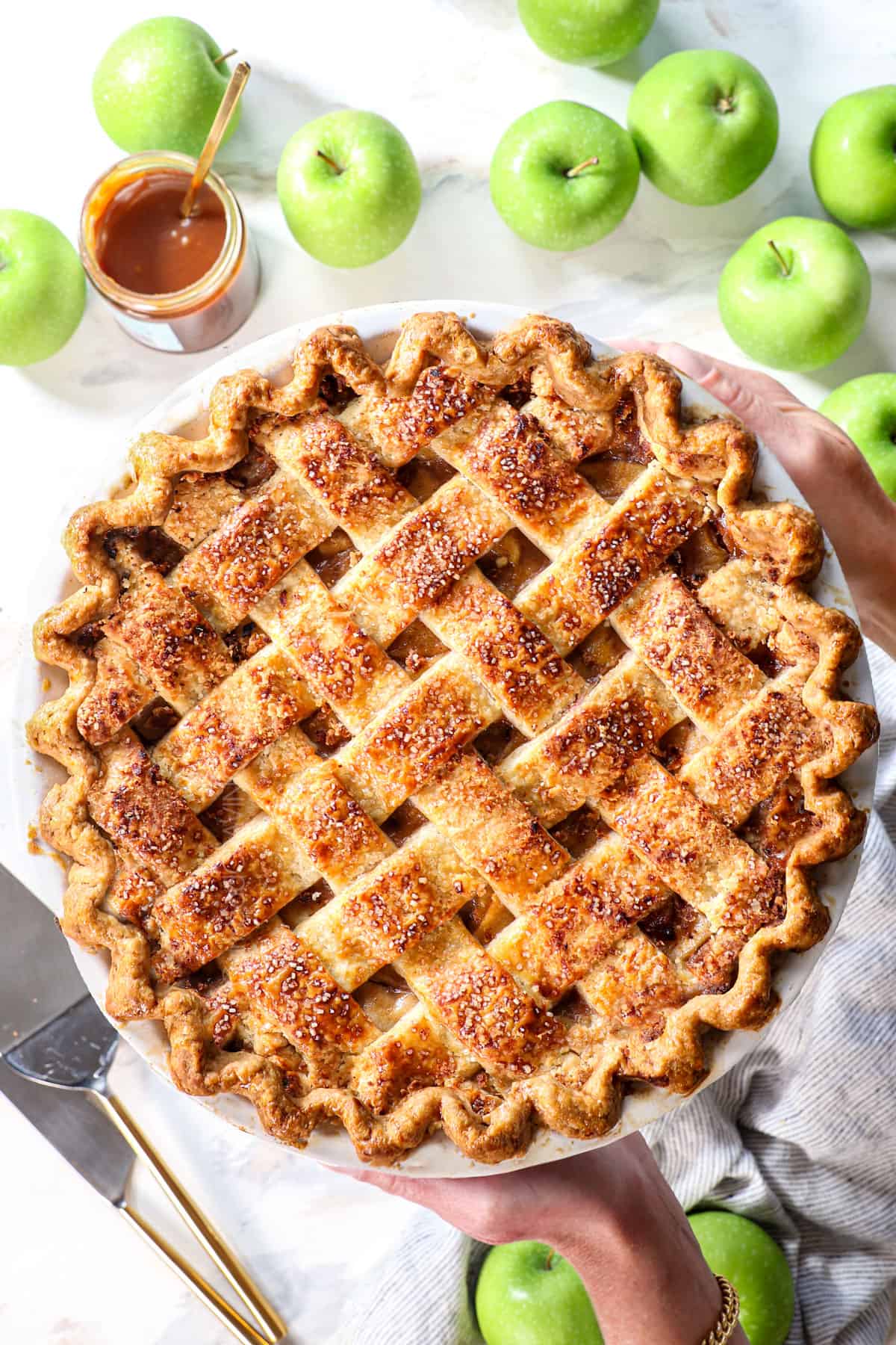 top view of two hands holding apple pie showing the lattice top