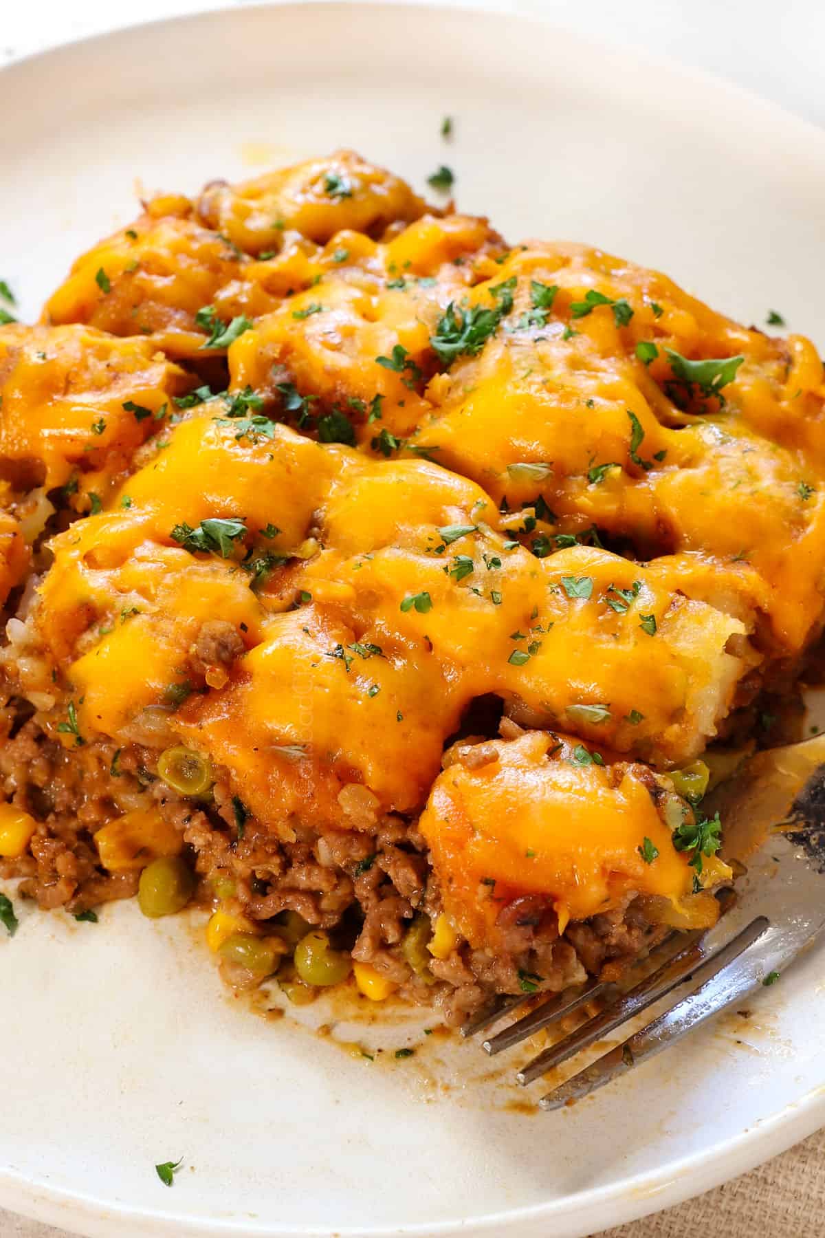 serving tater tot casserole on a plate garnished with parsley