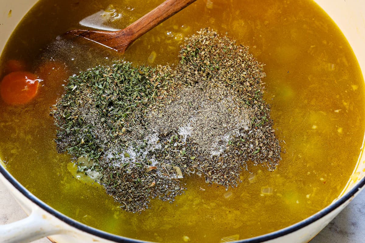 showing how to make turkey soup by adding spices, chicken bouillon, and chicken broth to the pot and simmering