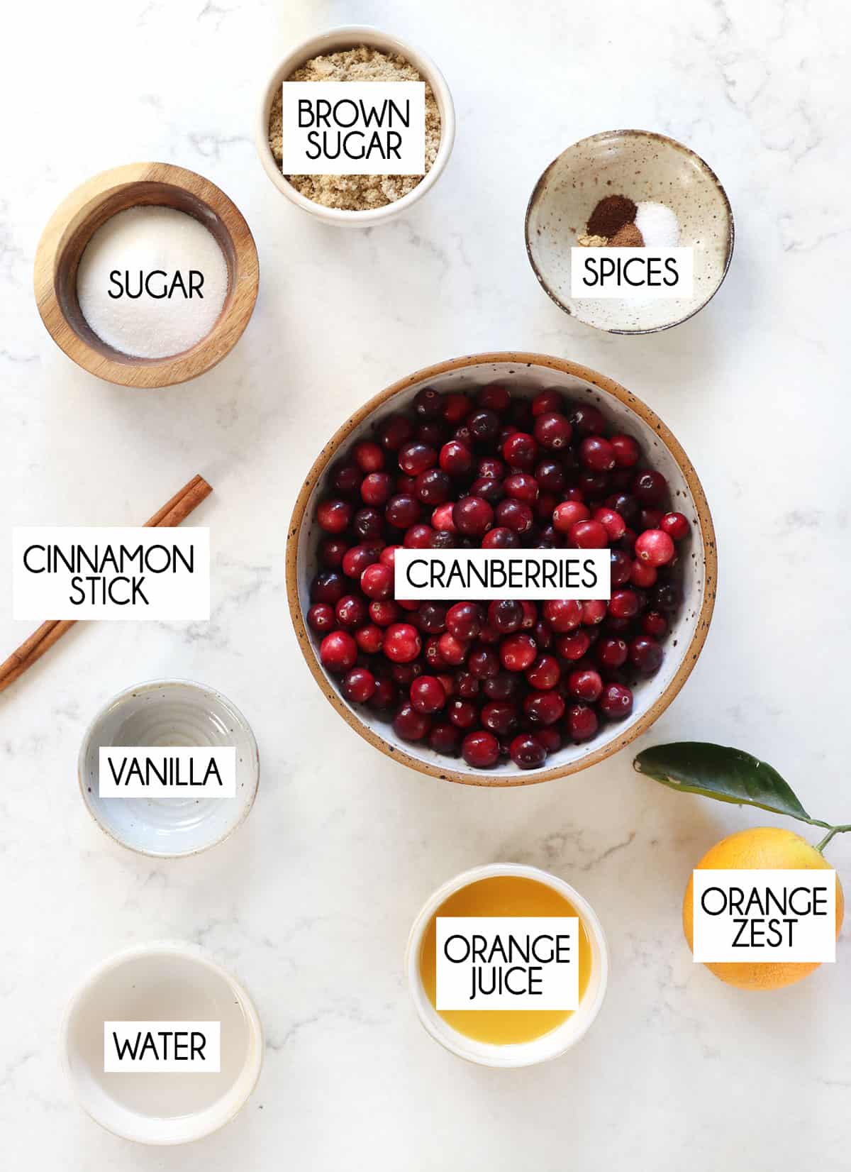 top view of cranberry sauce ingredients:  fresh cranberries, orange juice, sugar, brown sugar, vanilla, cinnamon