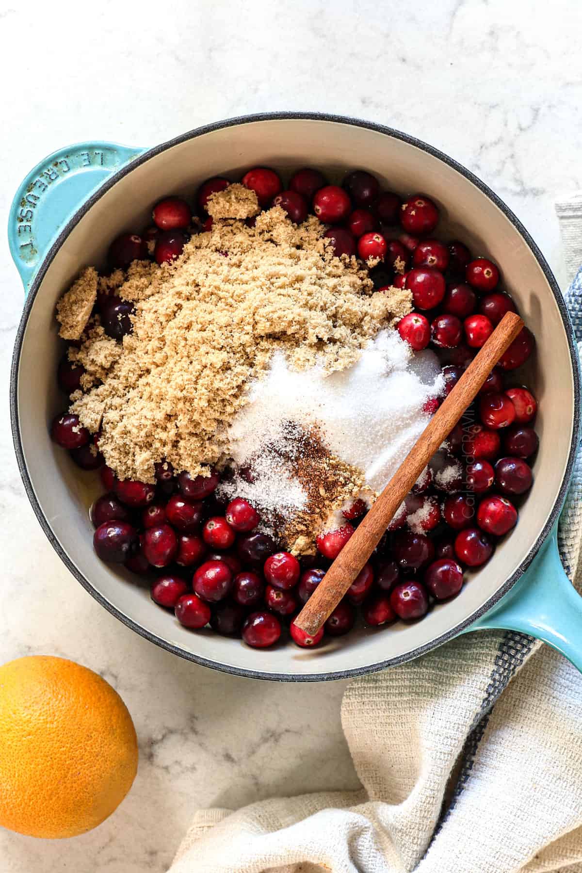 showing how to make cranberry sauce by adding fresh cranberries, orange juice, water, brown sugar, granulated sugar, spices, cinnamon to a saucepan