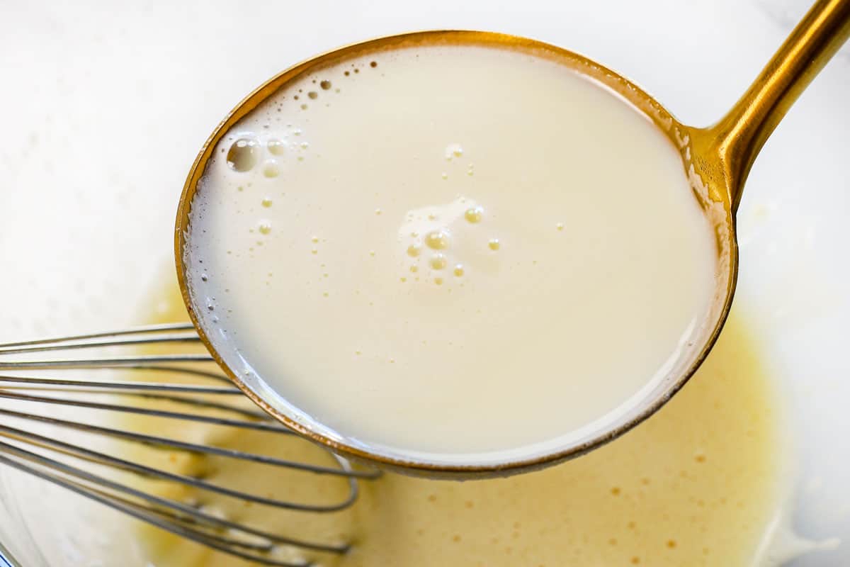 showing how to make custard pie by tempering the eggs by streaming the scalded milk into egg mixture