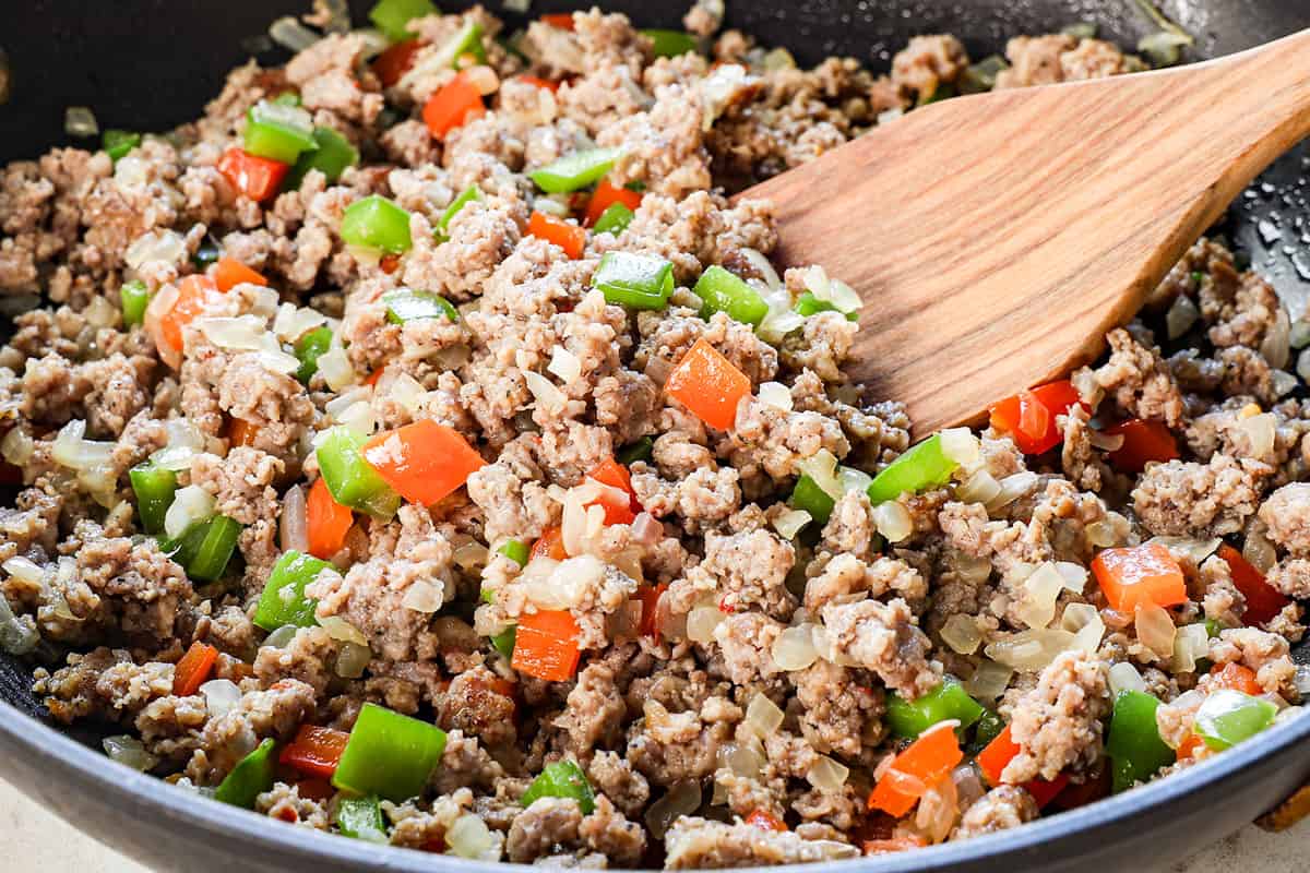 showing how to make crockpot breakfast casserole by browning the sausage, onions, garlic and bell peppers 