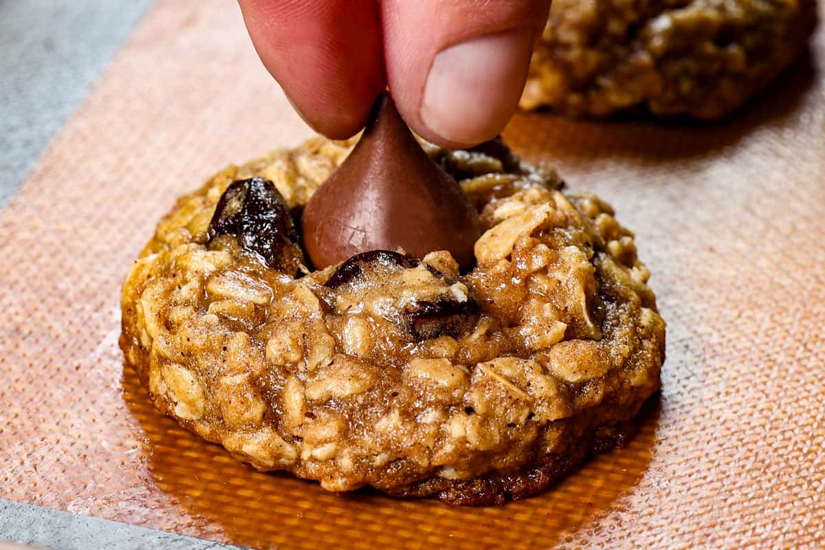 showing how to make cherry blossom cookie by adding the Hershey kisses to the center of each cookie