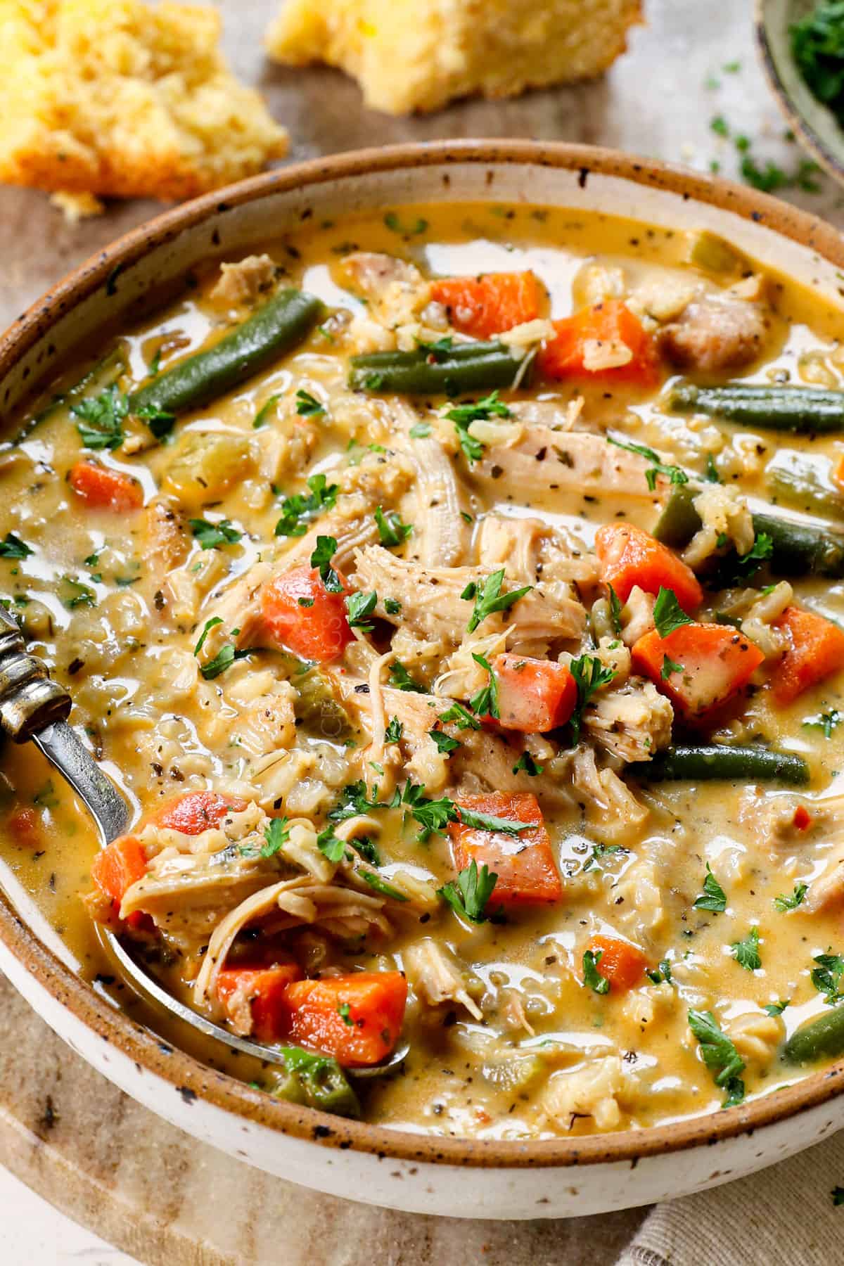 showing how to serve homemade chicken and rice soup garnished with fresh parsley and served with bread