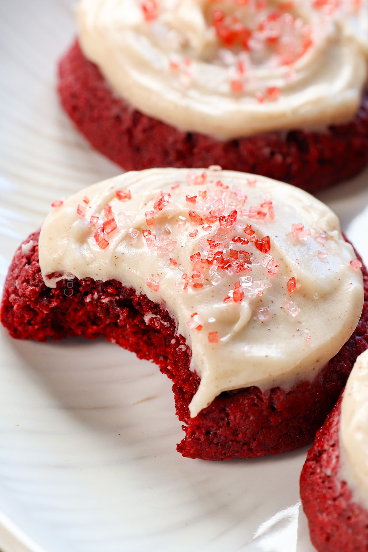 up close of red velvet cookies with a bite taken out showing how soft and chewy they are