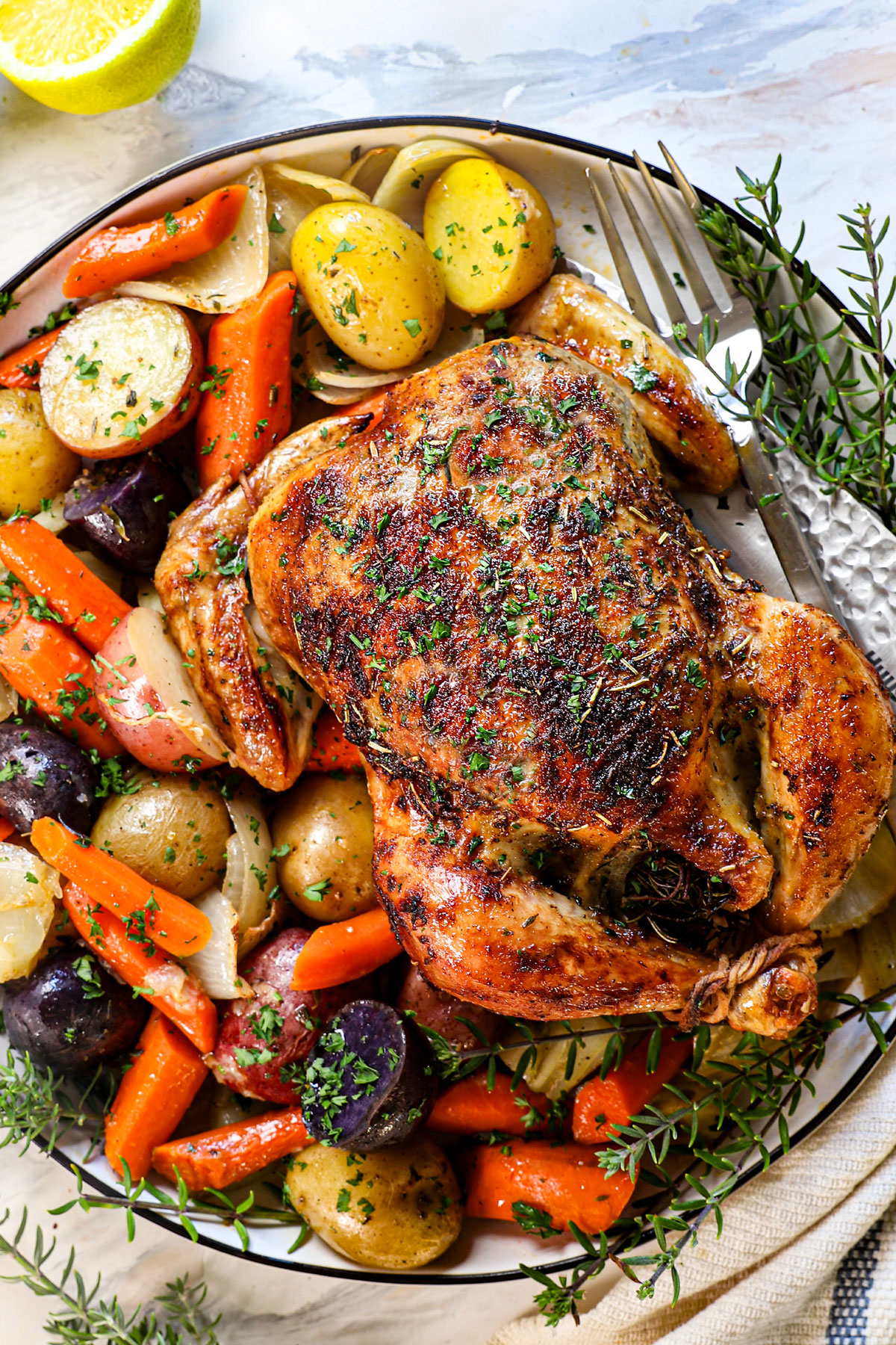 showing how to serve whole roasted chicken on a platter with potatoes, carrots and onions