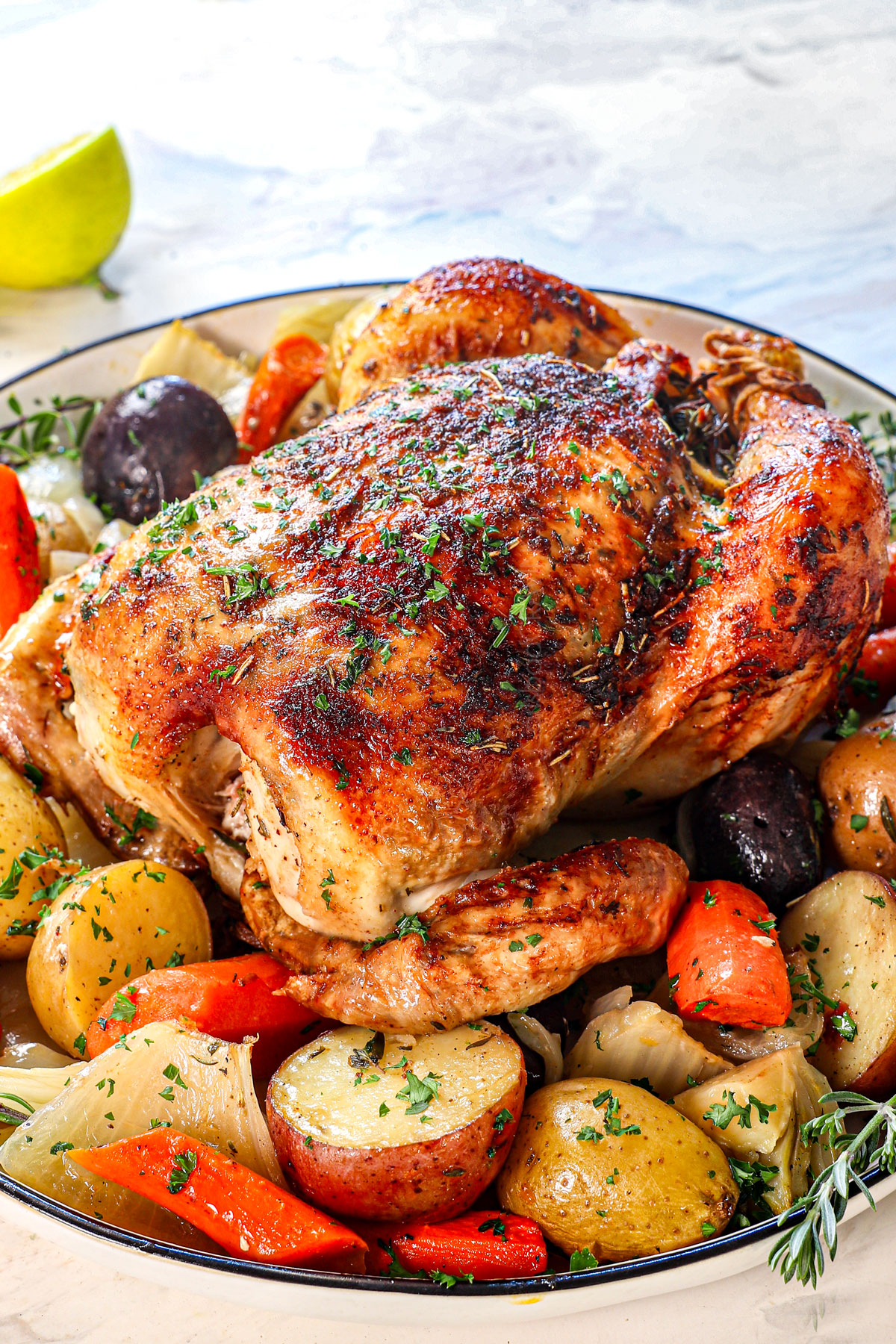 roast whole chicken being served with vegetables on a platter