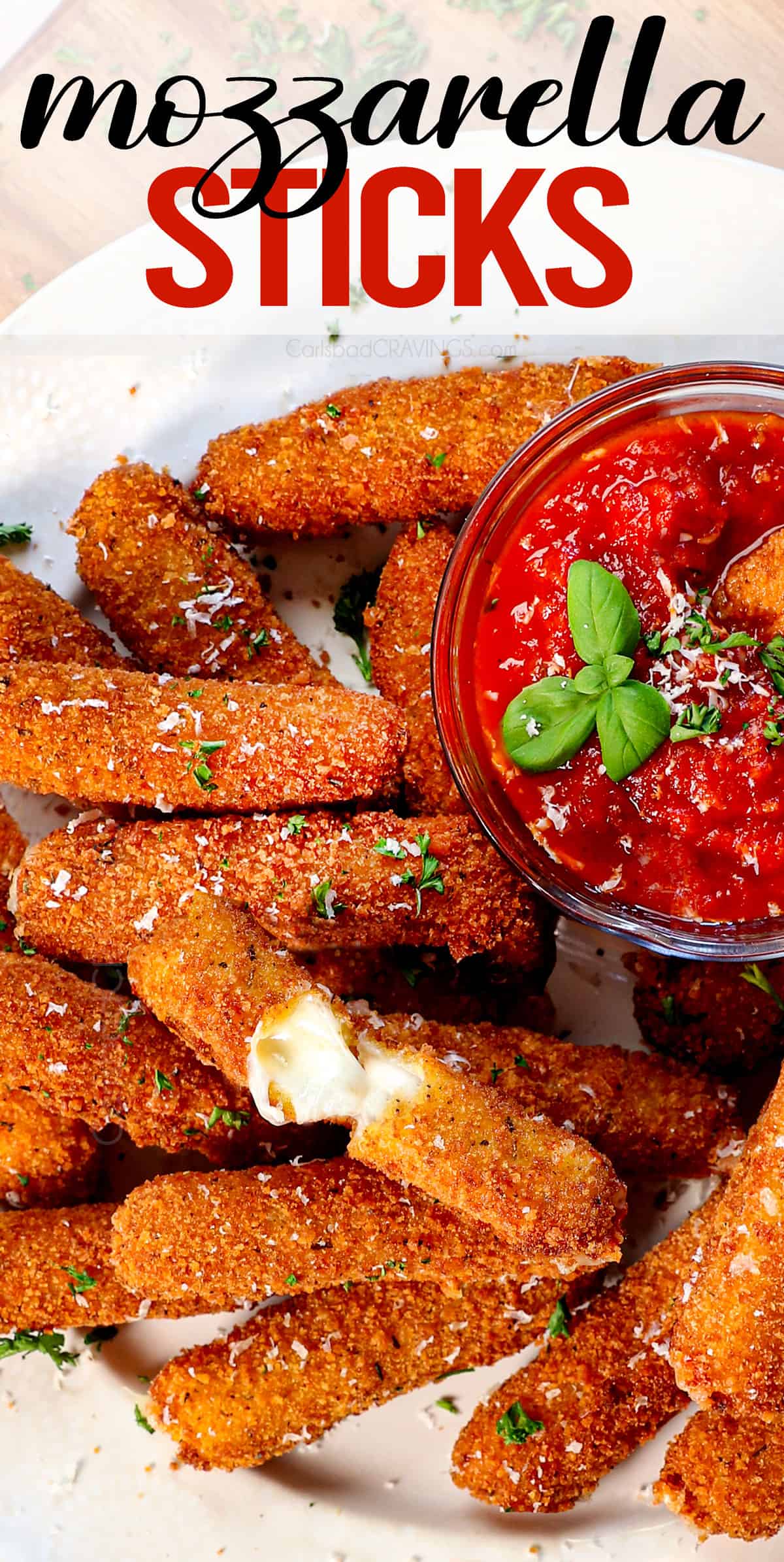 top view of serving mozzarella sticks on a platter with marinara with a cheese stick pulled apart showing the melty cheese