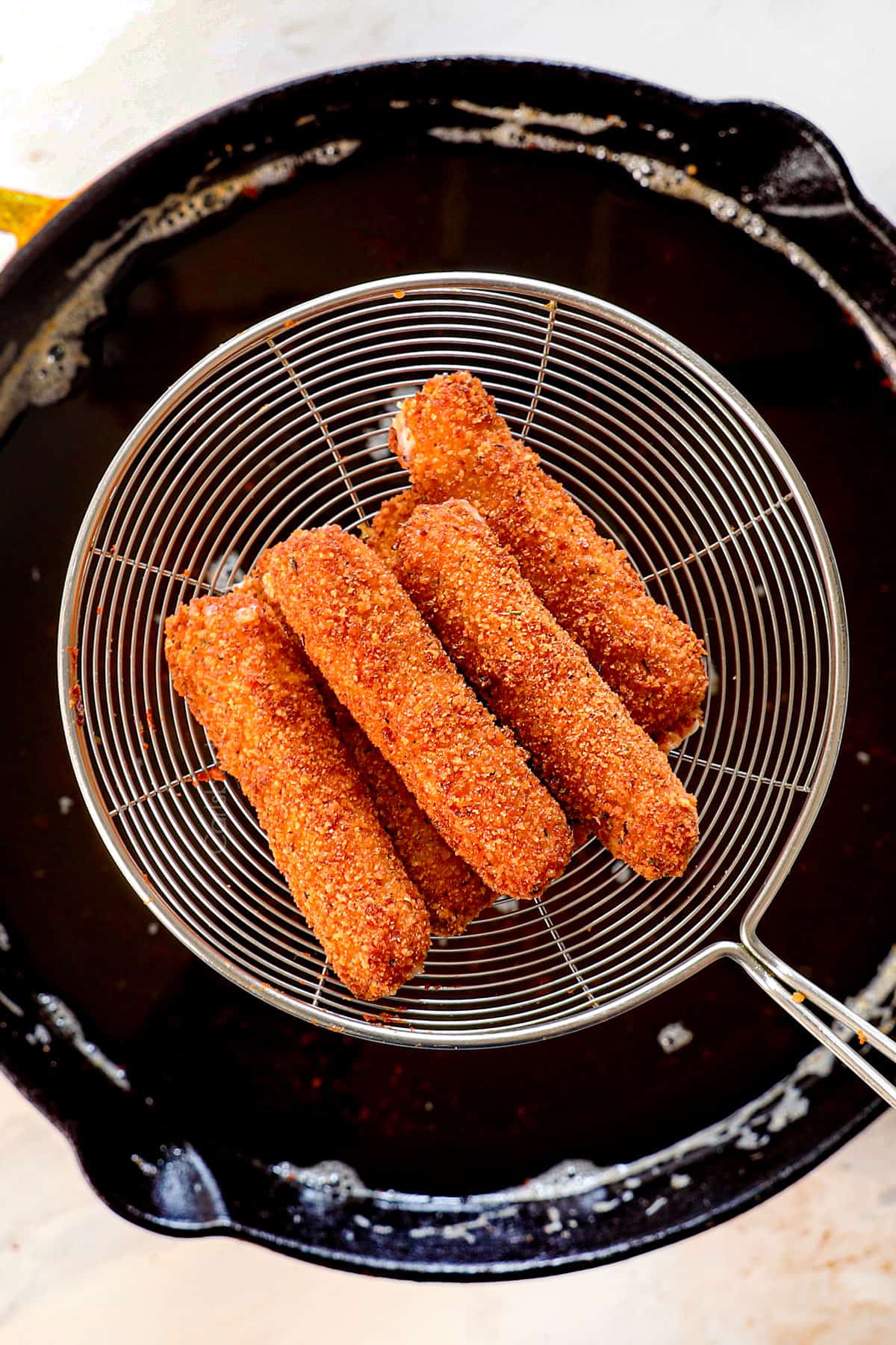 showing how to make mozzarella sticks by frying the mozzarella sticks until golden