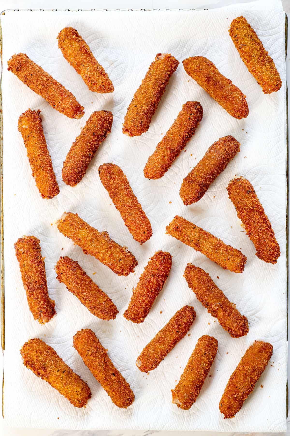 showing how to make mozzarella sticks by draining the cheese sticks on paper towels